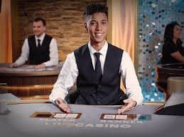 Dealer di meja baccarat langsung menunjukkan kartu-kartu di hadapan kamera